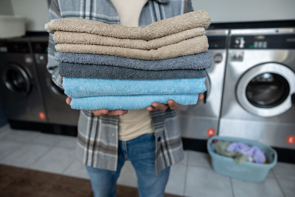 Person holding a stack of folded towels at EveryBuddy's Laundromat