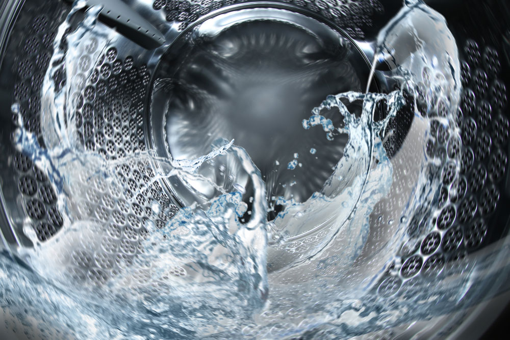 Water swirling inside a washing machine drum at EveryBuddy's Laundromat